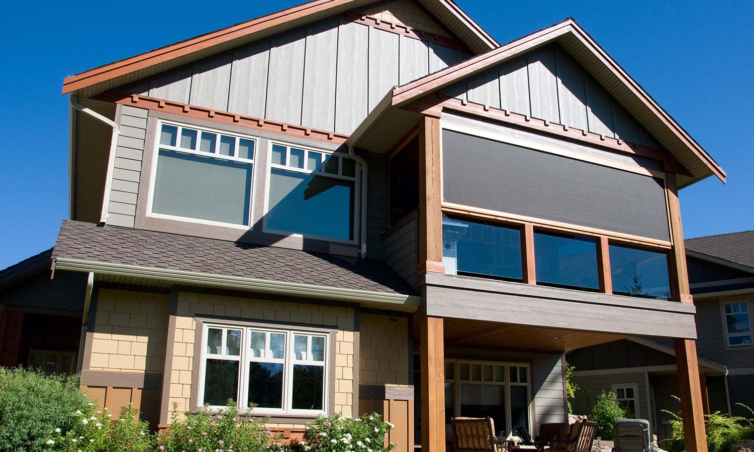 Two-story home exterior showing motorized exterior screens/shades covering an upper porch window.